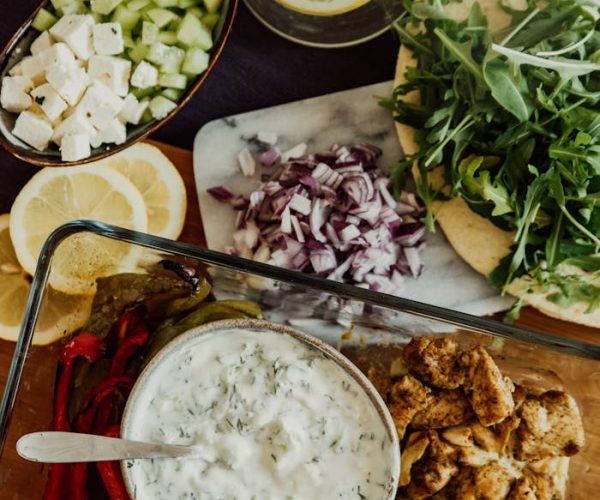A delicious Mediterranean salad with fresh veggies, grilled chicken, and creamy tzatziki sauce in a glass container.